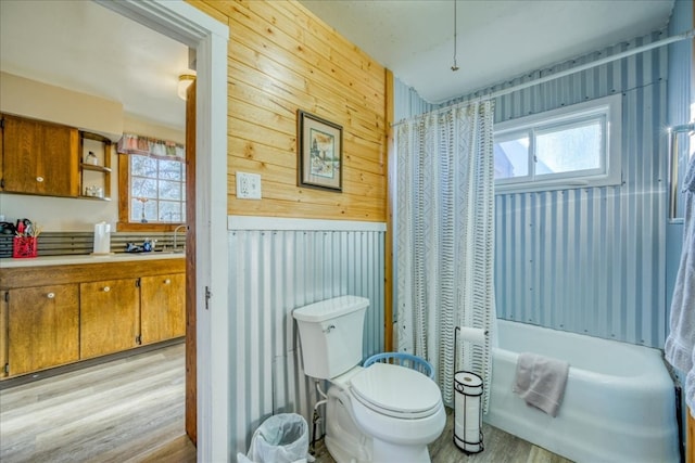 full bathroom with a tub to relax in, wooden walls, wood finished floors, and toilet