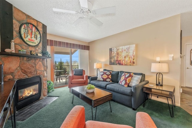 carpeted living room featuring a textured ceiling, a ceiling fan, and a fireplace