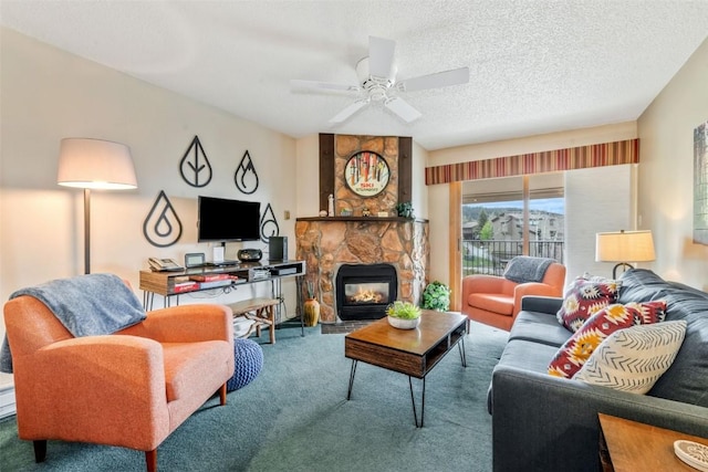 carpeted living room with ceiling fan, a stone fireplace, and a textured ceiling