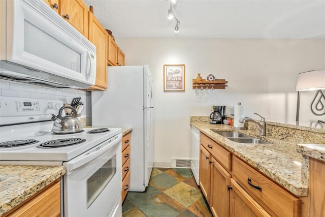 kitchen with white appliances, a sink, backsplash, baseboards, and light stone counters