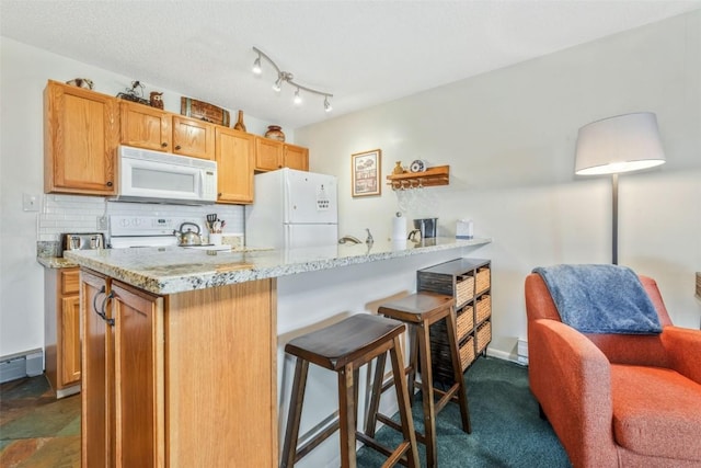 kitchen with white appliances, a kitchen breakfast bar, tasteful backsplash, light stone counters, and a peninsula