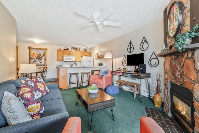 carpeted living room with a textured ceiling, a ceiling fan, and a fireplace
