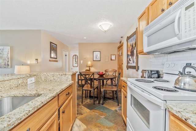 kitchen featuring white appliances, dark stone finish floors, a textured ceiling, tasteful backsplash, and light stone countertops