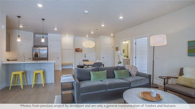 living area featuring baseboards, recessed lighting, and light wood-style floors