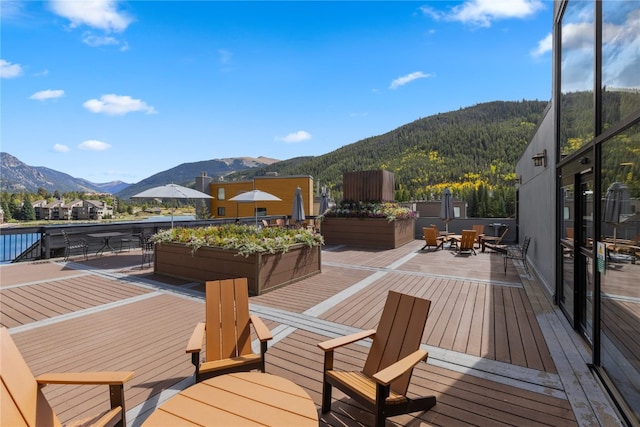 wooden deck with outdoor dining space and a mountain view