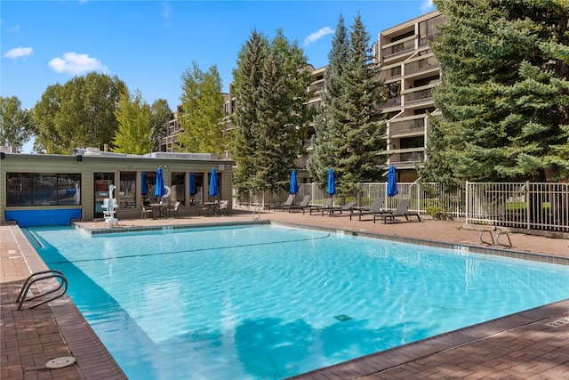 community pool with a patio and fence