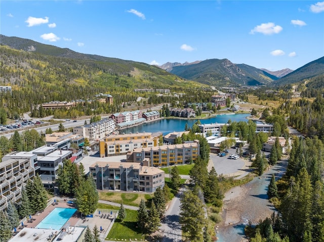 drone / aerial view featuring a wooded view and a water and mountain view
