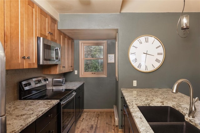 1120 Baldy Rd, Breckenridge, CO 80424 - kitchen with appliances with stainless steel finishes, light wood-type flooring, light stone countertops, brown cabinets, and backsplash