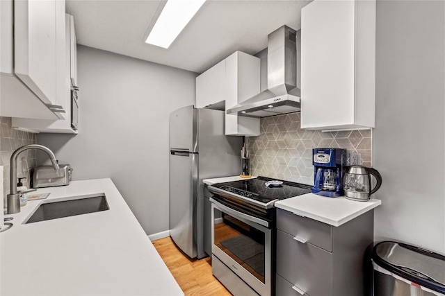 2350 Ski Trail Ln Unit 112, Steamboat Springs, CO 80487 - kitchen featuring wall chimney exhaust hood, appliances with stainless steel finishes, light countertops, white cabinets, and light wood-style flooring