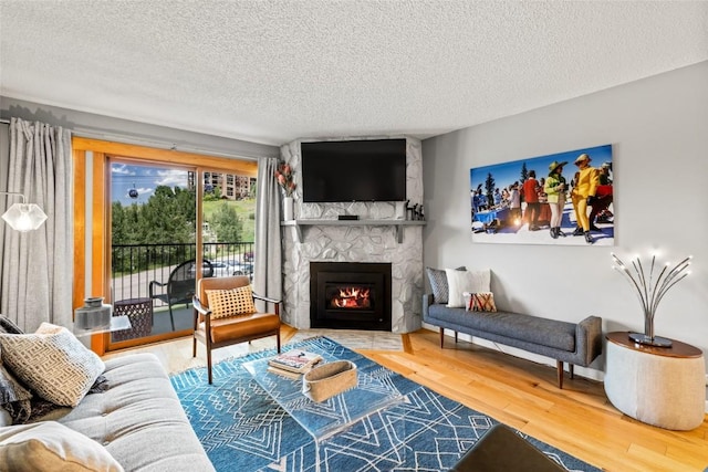 2350 Ski Trail Ln Unit 112, Steamboat Springs, CO 80487 - living area featuring a stone fireplace, a textured ceiling, and wood finished floors