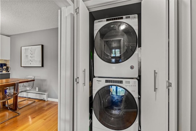 2350 Ski Trail Ln Unit 112, Steamboat Springs, CO 80487 - washroom with stacked washing machine and dryer, light wood-type flooring, a textured ceiling, and baseboard heating