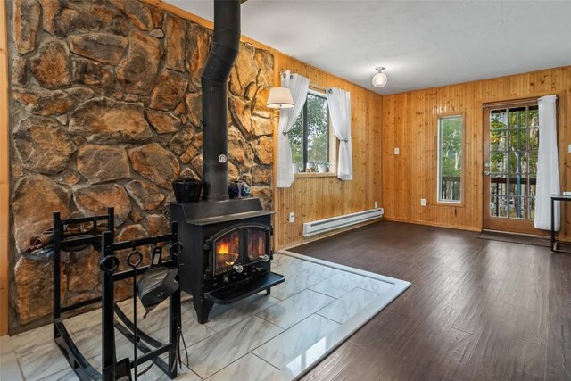 465 Mount Guyot Cir, Jefferson, CO 80456 - living room featuring wood finished floors, a wood stove, a baseboard heating unit, and a healthy amount of sunlight