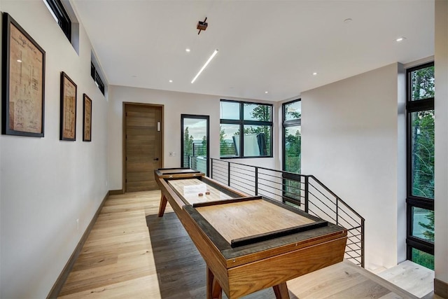 game room featuring a wealth of natural light, expansive windows, and light hardwood / wood-style floors