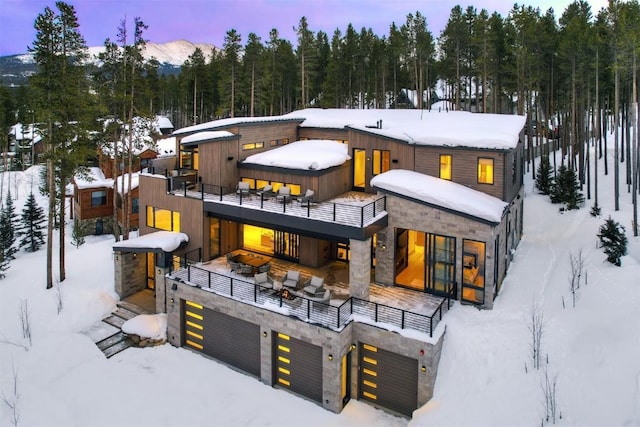 snow covered house featuring a balcony and a garage