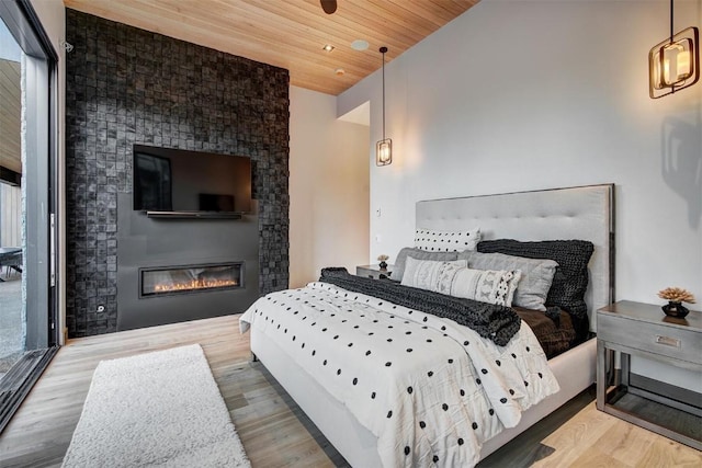 bedroom with a fireplace, light hardwood / wood-style flooring, and wood ceiling