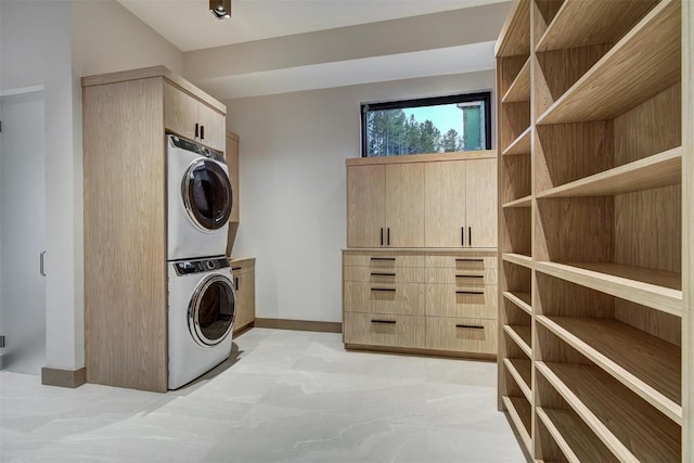 clothes washing area featuring cabinets and stacked washer and clothes dryer