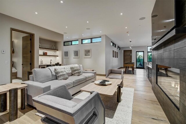 living room with a tiled fireplace and light wood-type flooring