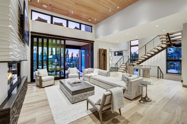 living room with light hardwood / wood-style floors, wood ceiling, and a towering ceiling