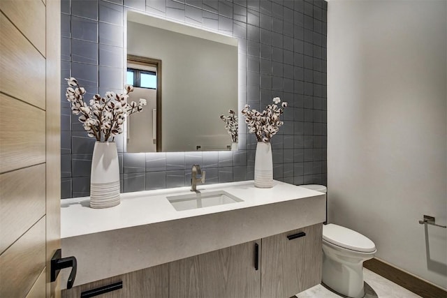 bathroom with vanity, toilet, and tile walls