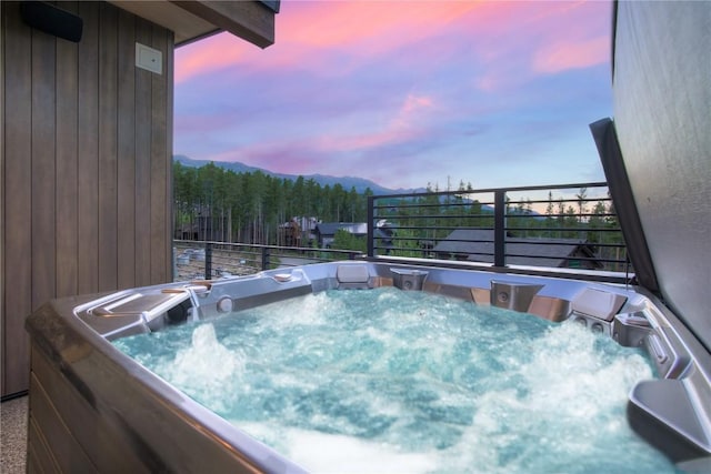 pool at dusk with a hot tub