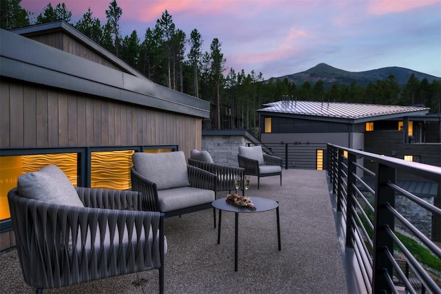 patio terrace at dusk featuring a mountain view, a balcony, and an outdoor living space