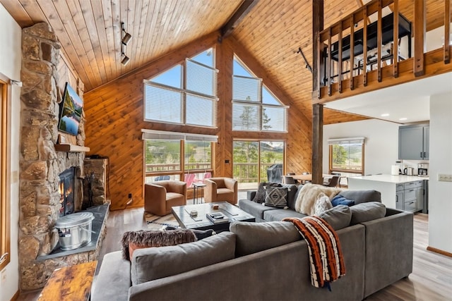 1009 American Way, Breckenridge, CO 80424 - living room with wooden ceiling with exposed beams, light wood-style floors, high vaulted ceiling, wooden walls, and a stone fireplace