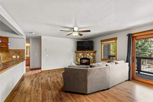 435 Ore House Plz Unit 202, Steamboat Springs, CO 80487 - living area featuring light wood-type flooring, a stone fireplace, baseboards, and a ceiling fan