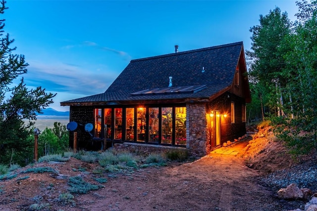 1023 Raven Way, Como, CO 80432 - rear view of property featuring stone siding, roof with shingles, and solar panels