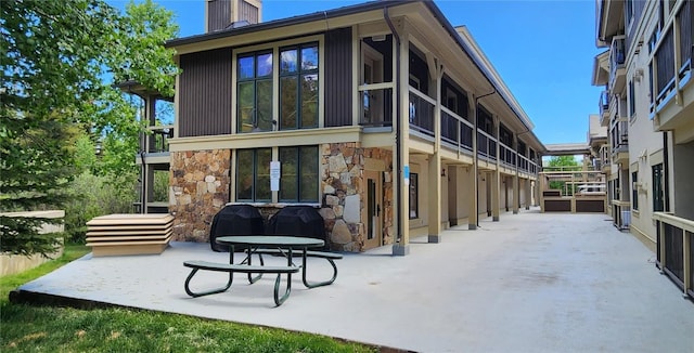 655 Four Oclock Rd Unit 209, Breckenridge, CO 80424 - rear view of house featuring stone siding, a patio area, and a chimney