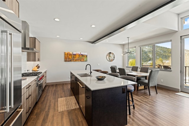 kitchen featuring a kitchen breakfast bar, premium appliances, a sink, modern cabinets, and a center island with sink