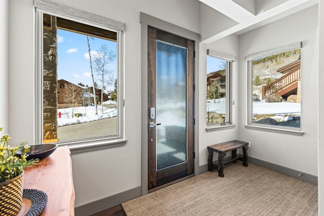 doorway to outside featuring plenty of natural light, carpet flooring, and baseboards