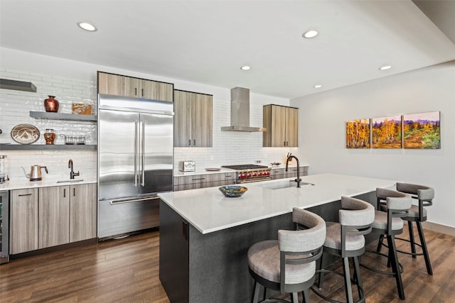 kitchen featuring high end appliances, a breakfast bar, modern cabinets, wall chimney exhaust hood, and tasteful backsplash