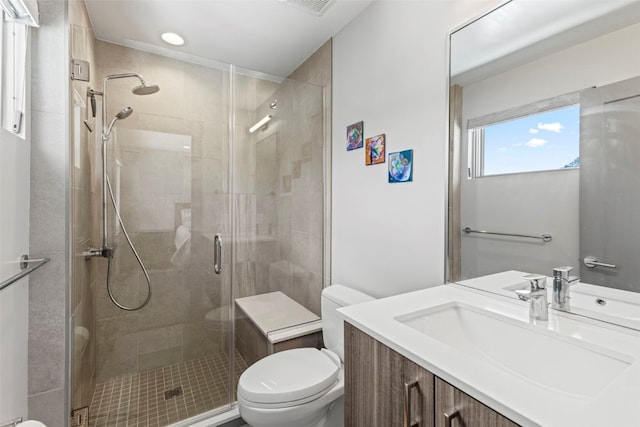 bathroom with a shower stall, toilet, vanity, and visible vents