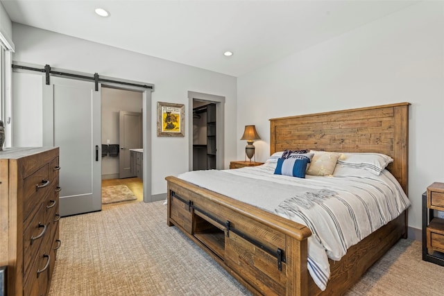 bedroom with a barn door, a closet, a walk in closet, light colored carpet, and recessed lighting