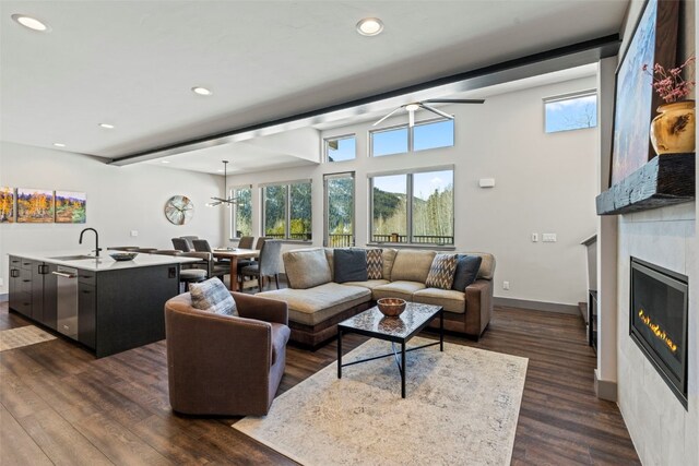 living area featuring recessed lighting, a glass covered fireplace, dark wood-style flooring, and ceiling fan
