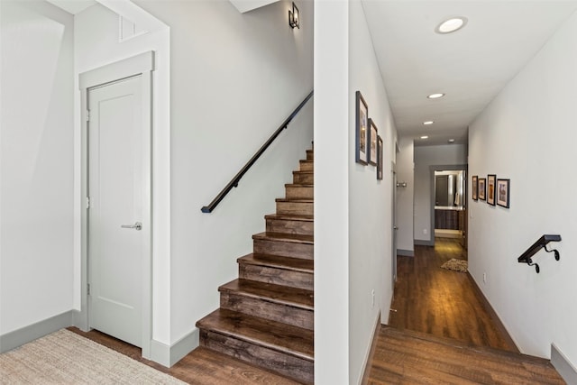 stairway featuring baseboards, wood finished floors, and recessed lighting
