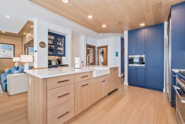 kitchen with light brown cabinetry, sink, a kitchen island with sink, wood ceiling, and light hardwood / wood-style floors