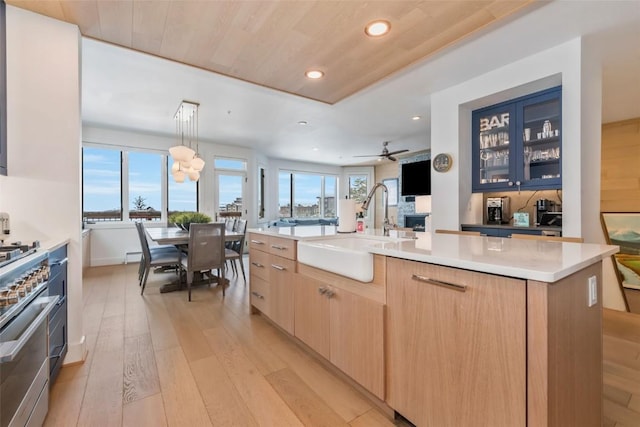 kitchen with sink, wood ceiling, light hardwood / wood-style flooring, ceiling fan, and a center island with sink