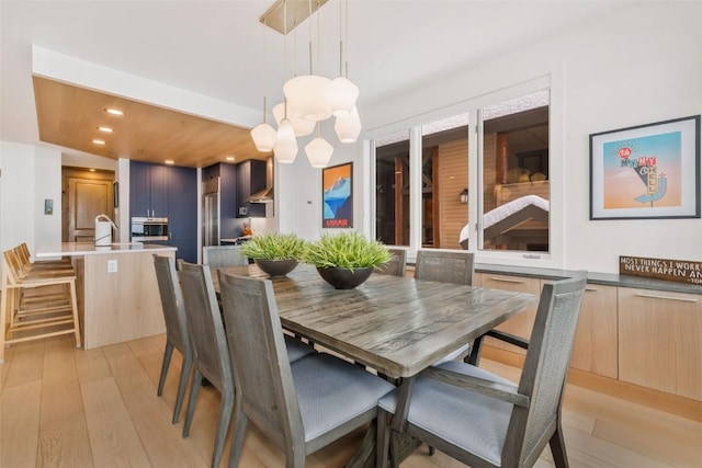 dining area with light hardwood / wood-style floors and a notable chandelier