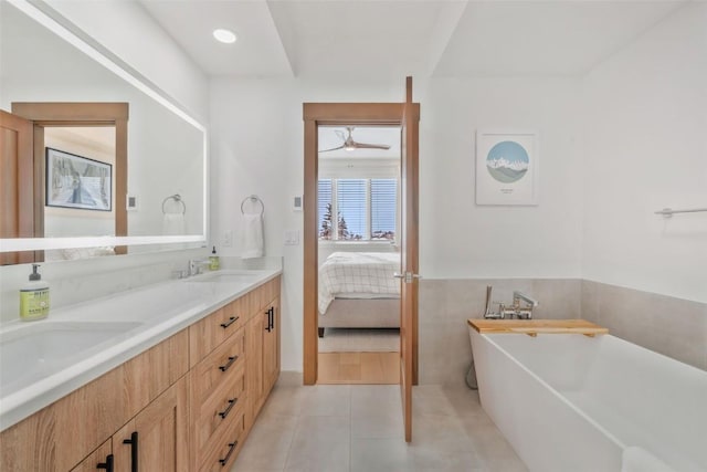 bathroom featuring tile patterned flooring, vanity, a tub, and tile walls