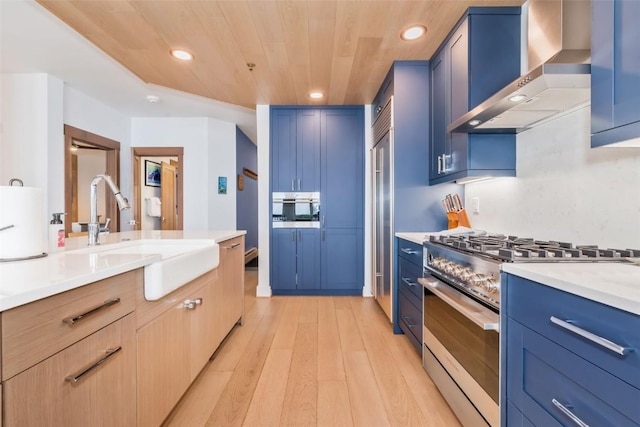 kitchen featuring blue cabinetry, high end stainless steel range, sink, wood ceiling, and wall chimney range hood