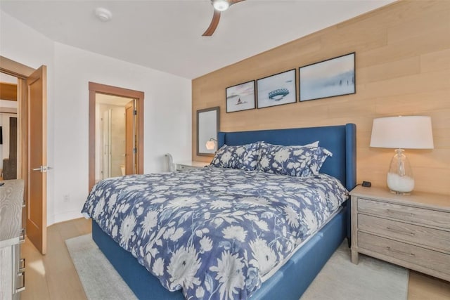 bedroom with wooden walls, ceiling fan, and light wood-type flooring