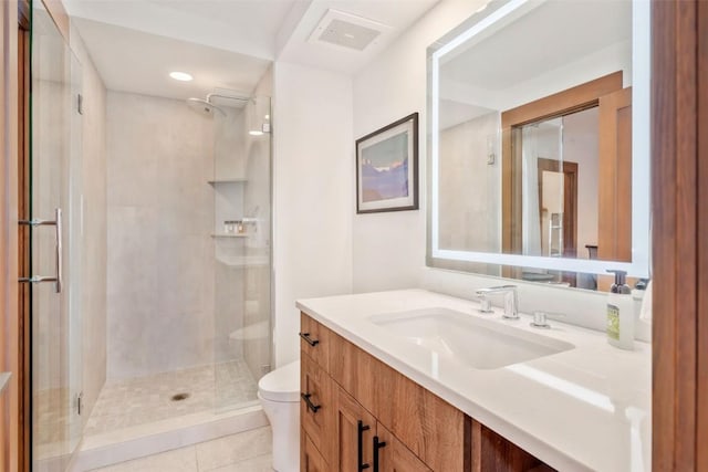 bathroom with vanity, a shower with shower door, tile patterned floors, and toilet