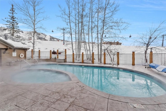 snow covered pool with a mountain view and a patio area