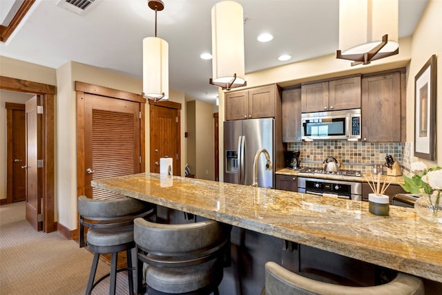 1521 Ski Hill Rd Unit 8313, Breckenridge, CO 80424 - kitchen with appliances with stainless steel finishes, a kitchen bar, decorative backsplash, light carpet, and light stone countertops