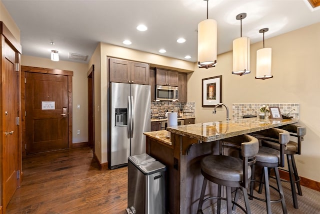 1521 Ski Hill Rd Unit 8313, Breckenridge, CO 80424 - kitchen featuring appliances with stainless steel finishes, a peninsula, dark wood-type flooring, a breakfast bar, and backsplash