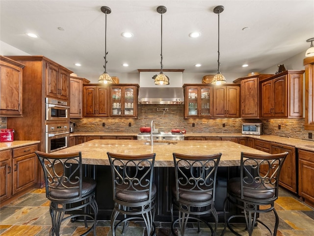 585 Independence Rd, Keystone, CO 80435 - kitchen featuring ventilation hood, stone tile flooring, stainless steel microwave, recessed lighting, and an island with sink