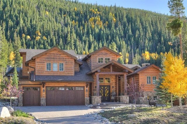 585 Independence Rd, Keystone, CO 80435 - log-style house featuring a forest view, roof with shingles, a garage, stone siding, and asphalt driveway