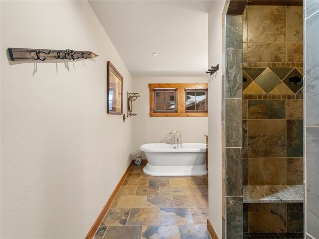585 Independence Rd, Keystone, CO 80435 - bathroom with stone tile floors, a soaking tub, baseboards, and a walk in shower