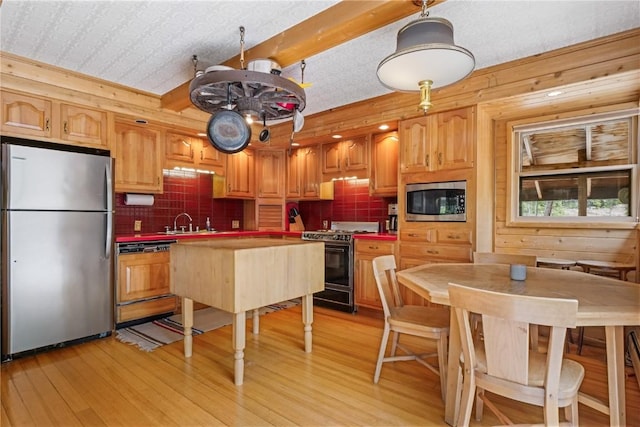 212 Briar Rose Ln, Breckenridge, CO 80424 - kitchen with appliances with stainless steel finishes, light wood-style floors, tasteful backsplash, wooden walls, and a sink
